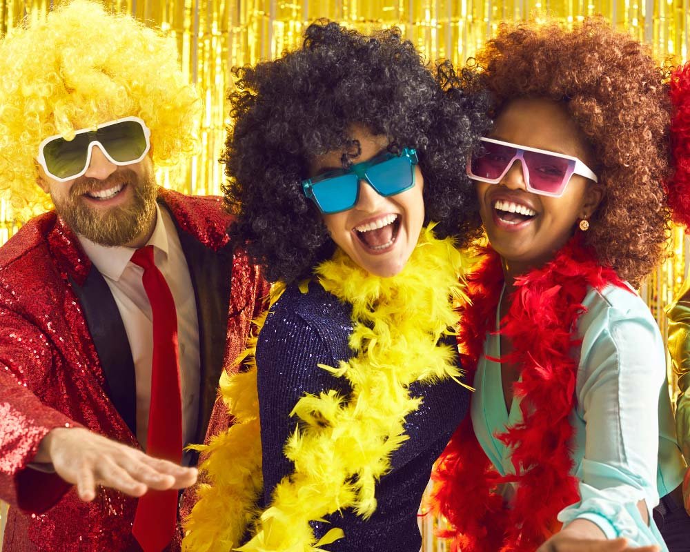 Invités déguisés avec perruques et boas lors d’une soirée