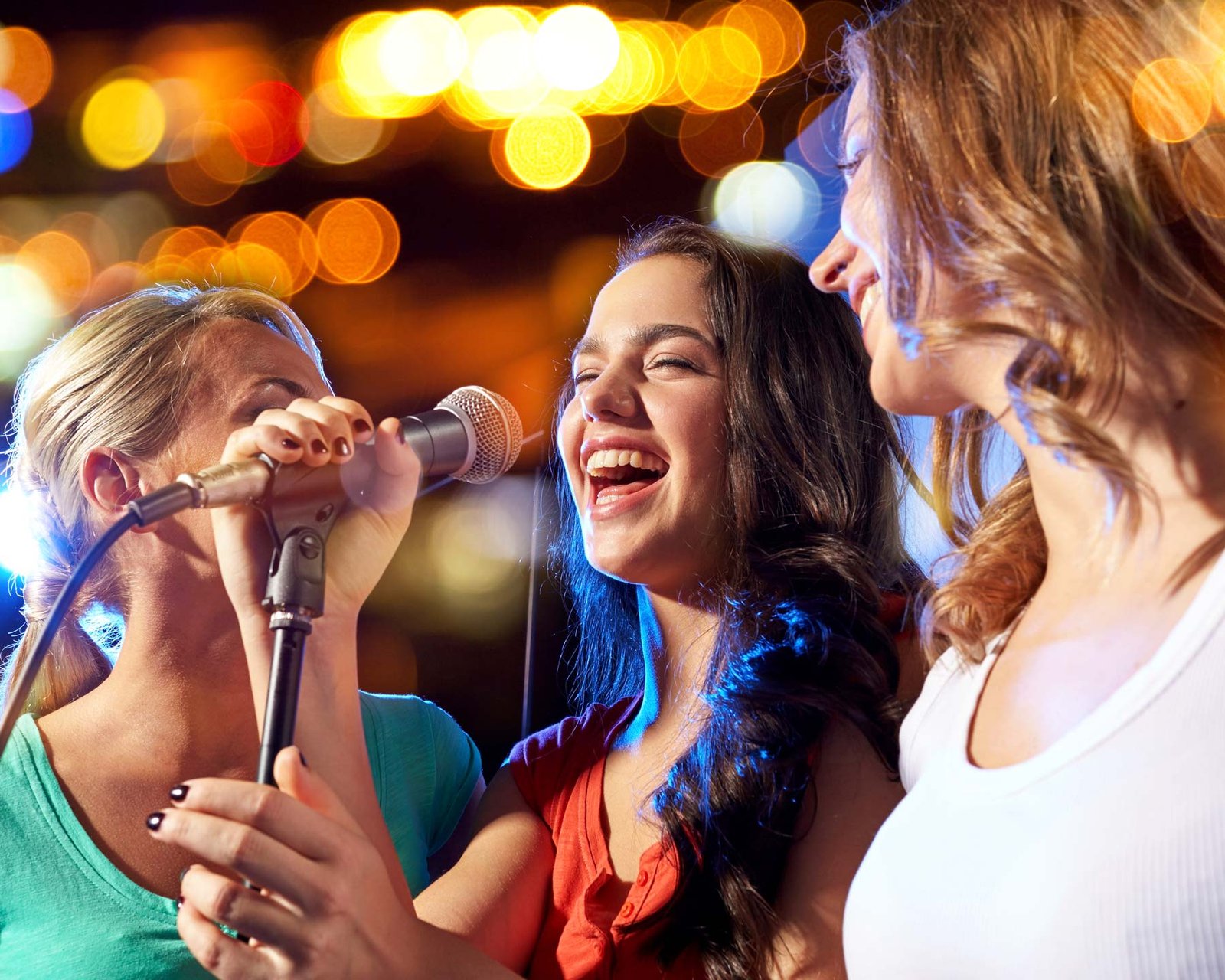 Jeunes femmes chantant au micro lors d’une soirée karaoké